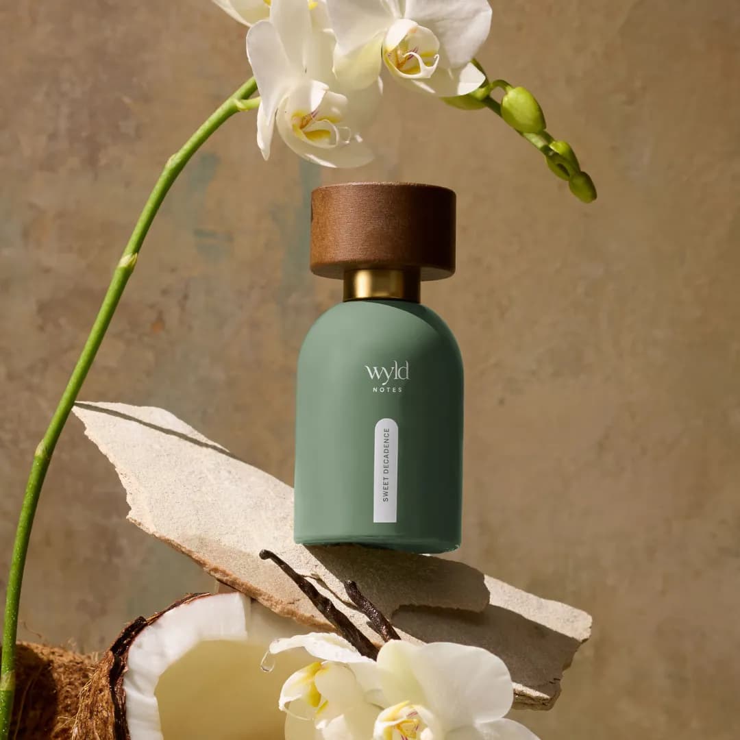 Sweet Decadence von Wyld Notes neben Orchidee und aufgebrochener Kokosnuss